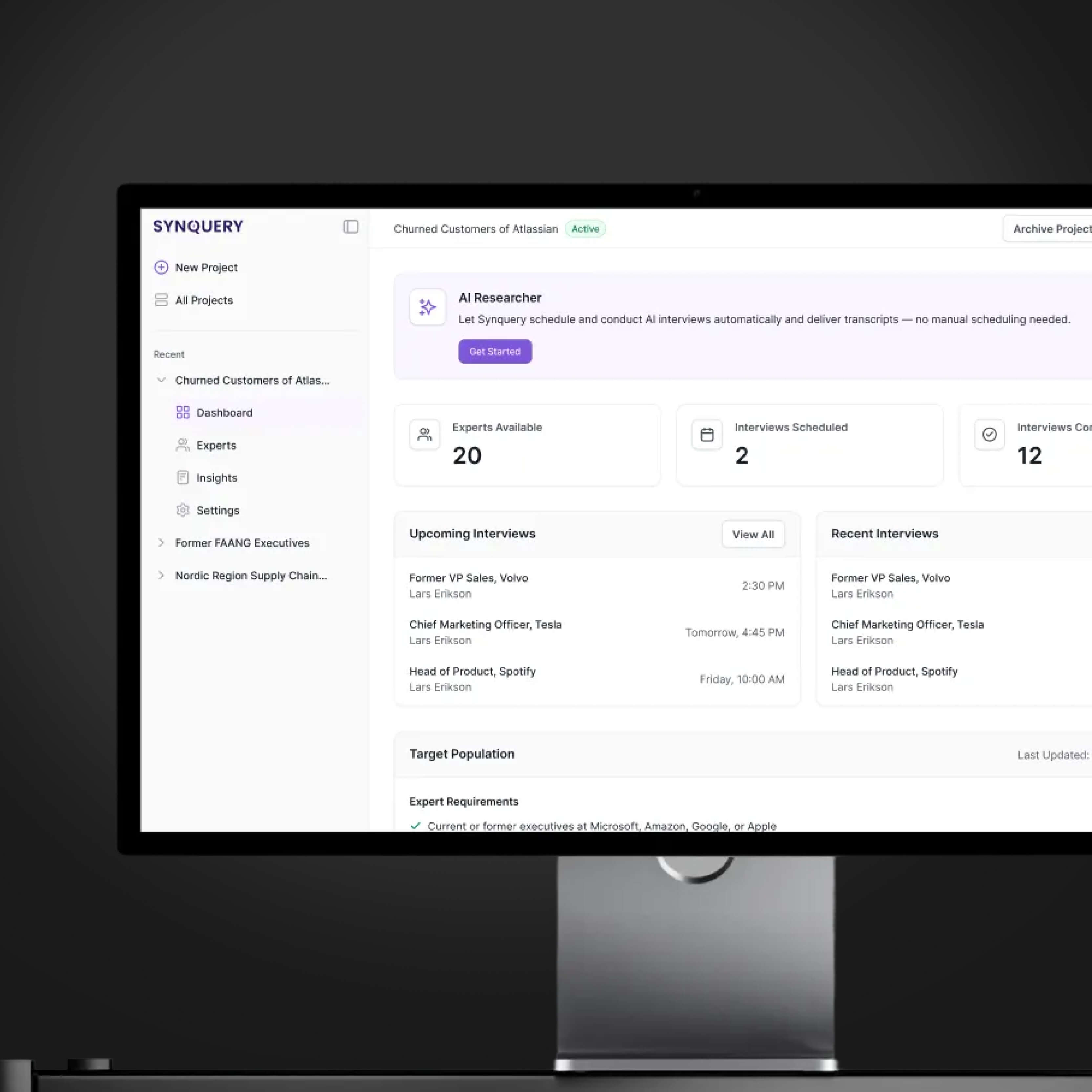 Synquery dashboard on a monitor showing the "Churned Customers of Atlassian" project with 20 experts available, 2 interviews scheduled, 12 completed, and lists of upcoming and recent expert interviews